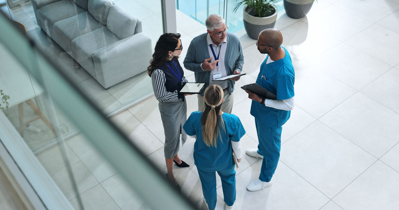 Ärzteteam und Fachkräfte besprechen sich stehend in einer Klinik.