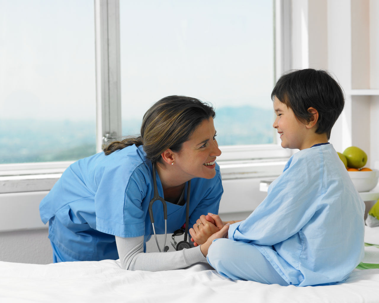 Infirmière souriant à un jeune patient hospitalisé.
