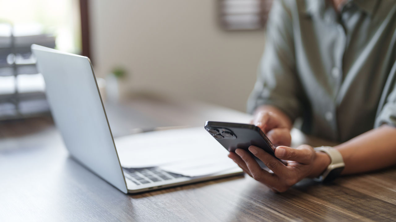 Personne travaillant avec un ordinateur portable et un smartphone.