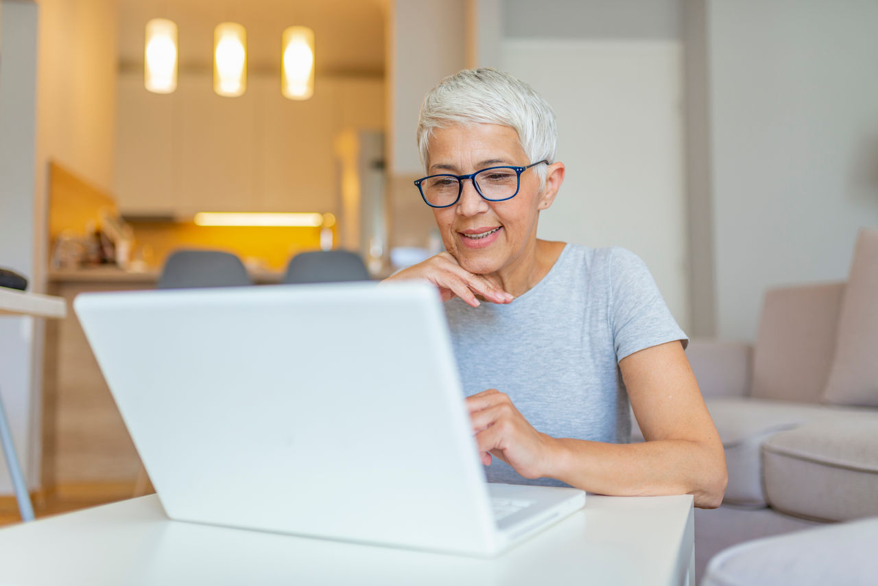 Femme âgée utilisant un ordinateur portable dans un salon.